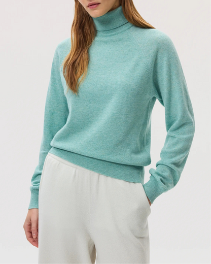 Model wears Johnstons of Elgin SS25 Women's Knitwear Jade Classic Cashmere Roll Neck Sweater with white culottes KAP05275HC4284