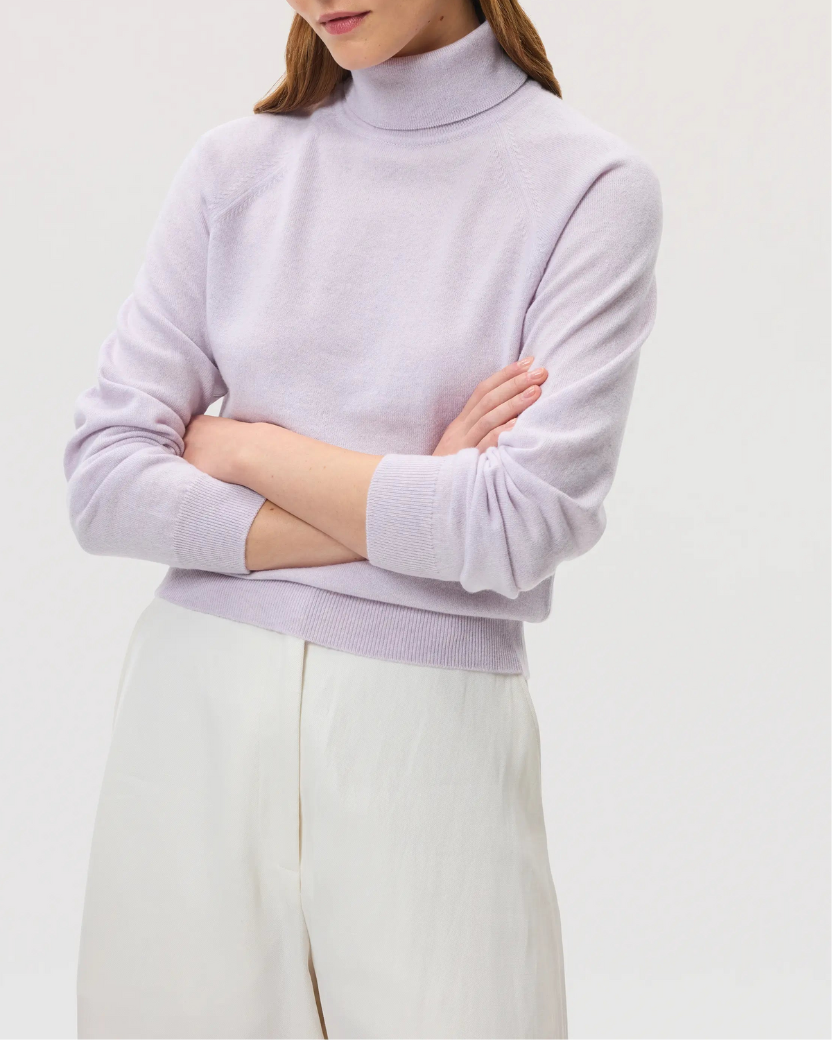 Model wears Johnstons of Elgin SS25 Women's Knitwear Lavender Classic Cashmere Roll Neck Jumper with white trousers KAP05275HD0086