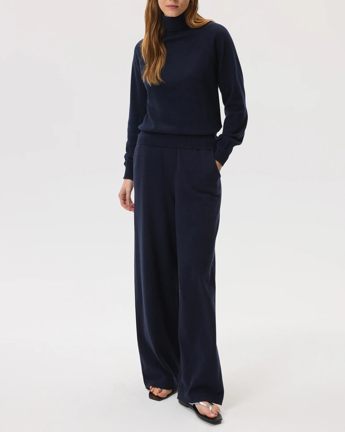 Model wears Johnstons of Elgin SS25 Women's Knitwear Navy Classic Cashmere Roll Neck Sweater with matching cashmere culottes on a white background  KAP05275SD7286