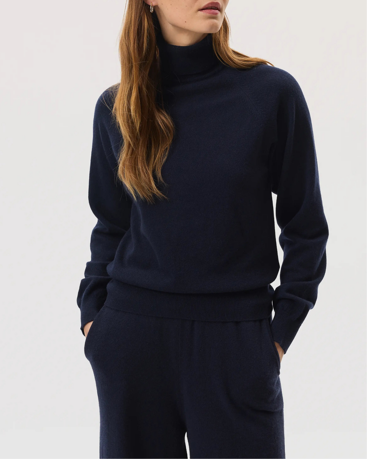 Model wears Johnstons of Elgin SS25 Women's Knitwear Navy Classic Cashmere Roll Neck Sweater with matching cashmere culottes KAP05275SD7286