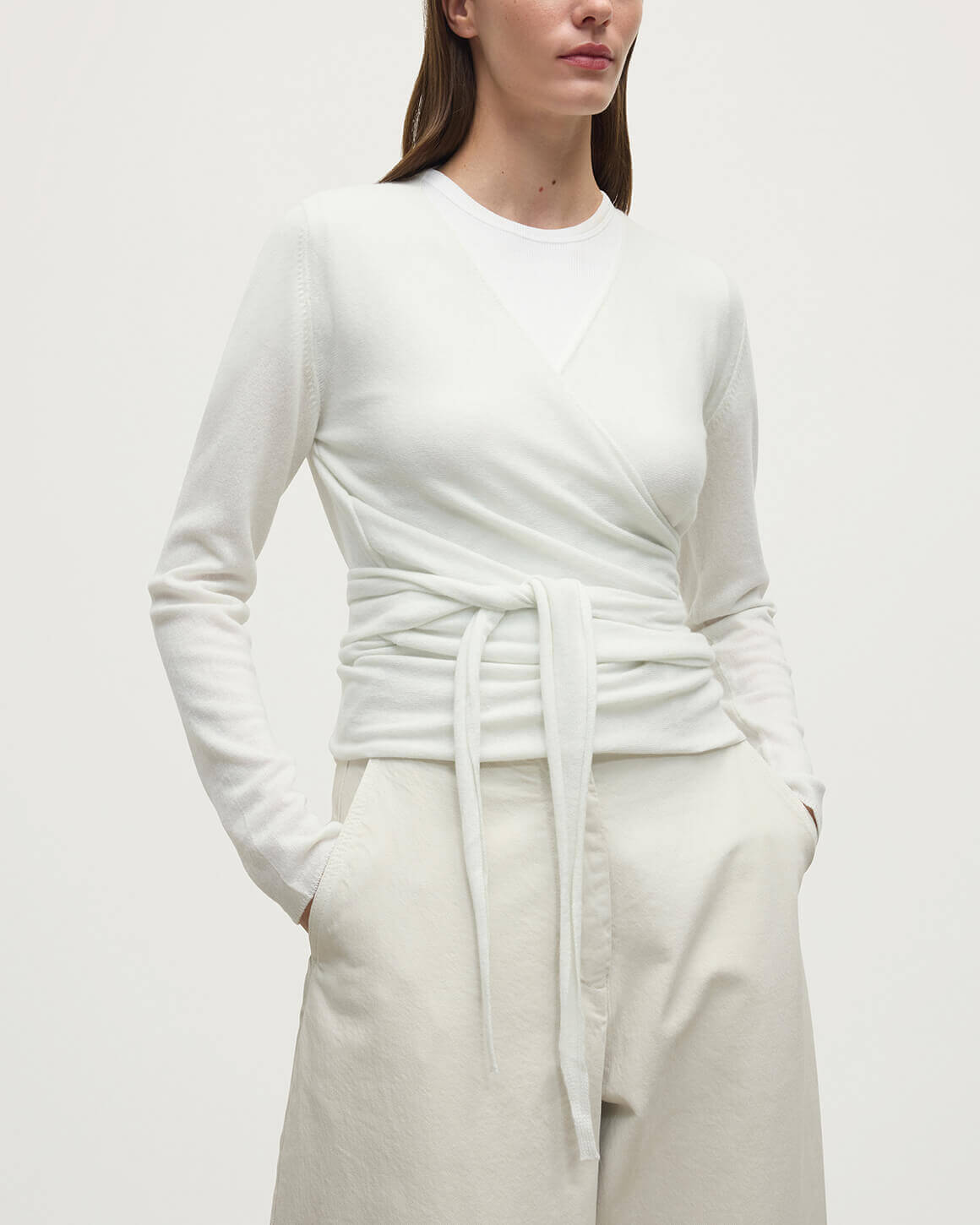 Model wearing Johnstons of Elgin AW25 Women's Knitwear White Featherlight Cashmere Ballet Wrap with white trousers on a light background KAP05408HA0371