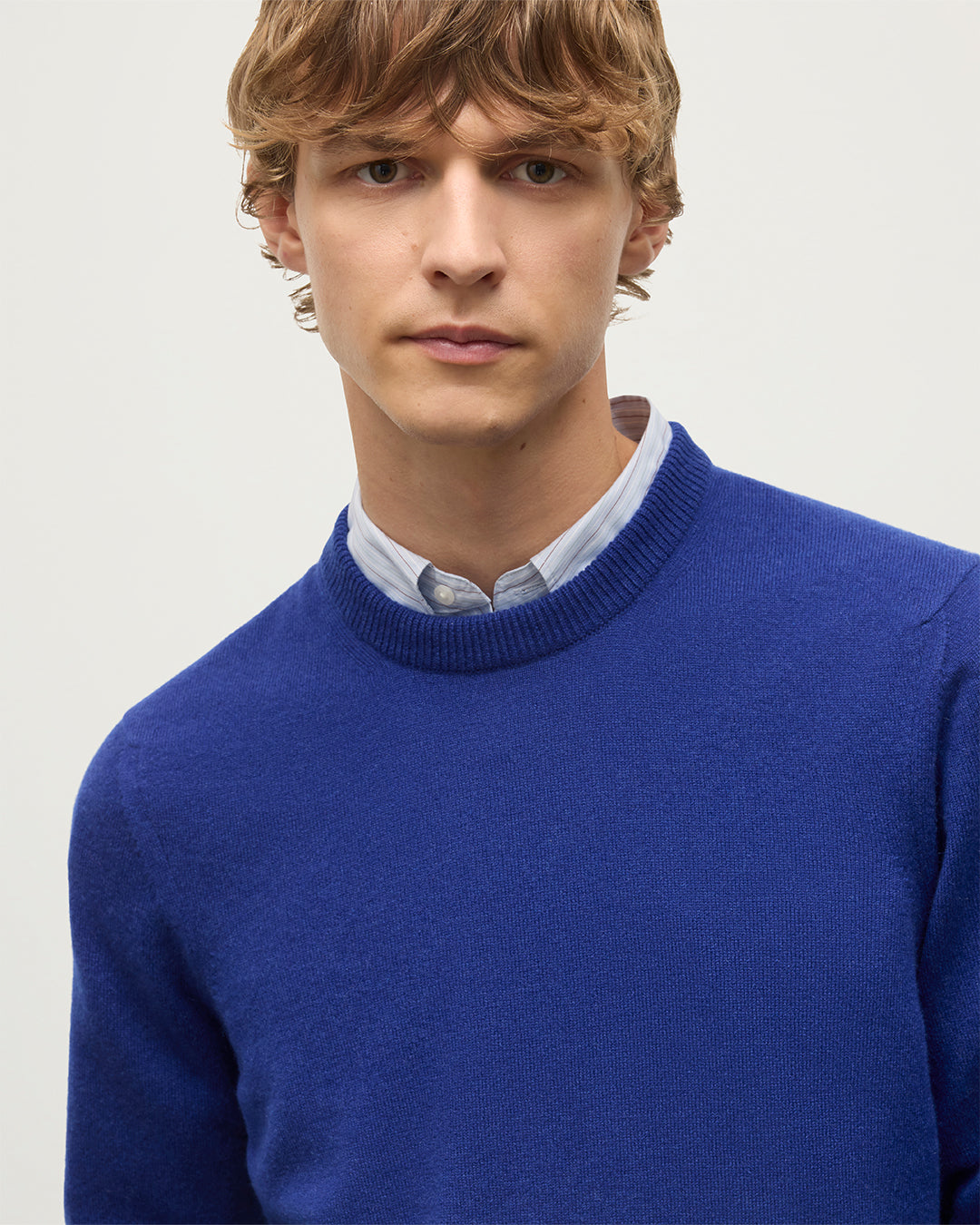 MODEL WEARS JOHNSTONS OF ELGIN MENS RORY CREW CLASSIC JUMPER BLUE 100% CASHMERE OVER A LIGHT BLUE SHIRT KAP05471SD5326