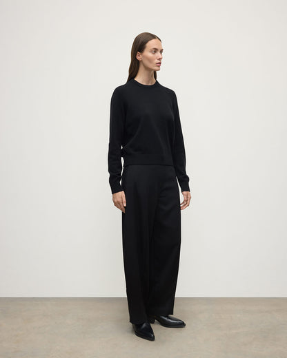 Model wears Johnstons of Elgin AW25 Women's Knitwear Black Classic Cashmere Black Round Neck Jumper Side View KAP05572SA7210
