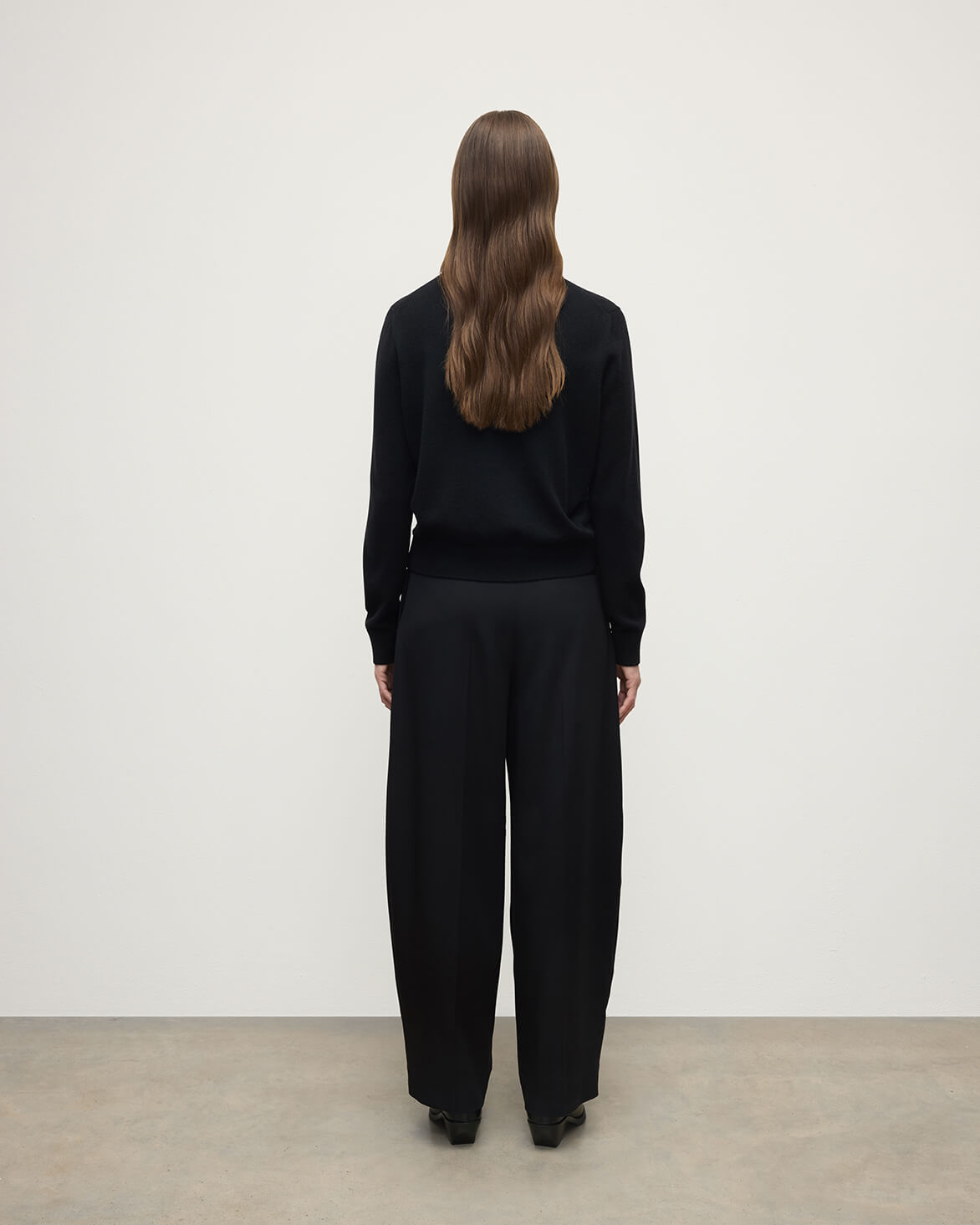 Model wears Johnstons of Elgin AW25 Women's Knitwear Black Classic Cashmere Black Round Neck Jumper Back View KAP05572SA7210