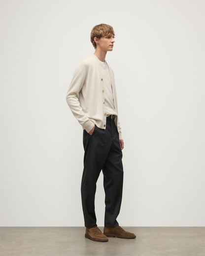 MODEL WEARS JOHNSTONS OF ELGIN MENS RORY VEE NECK CLASSIC CARDIGAN NATURAL 100% CASHMERE OVER A MATCHING V NECK SWEATER WITH GREY TROIUSERS KAP05576HA0402