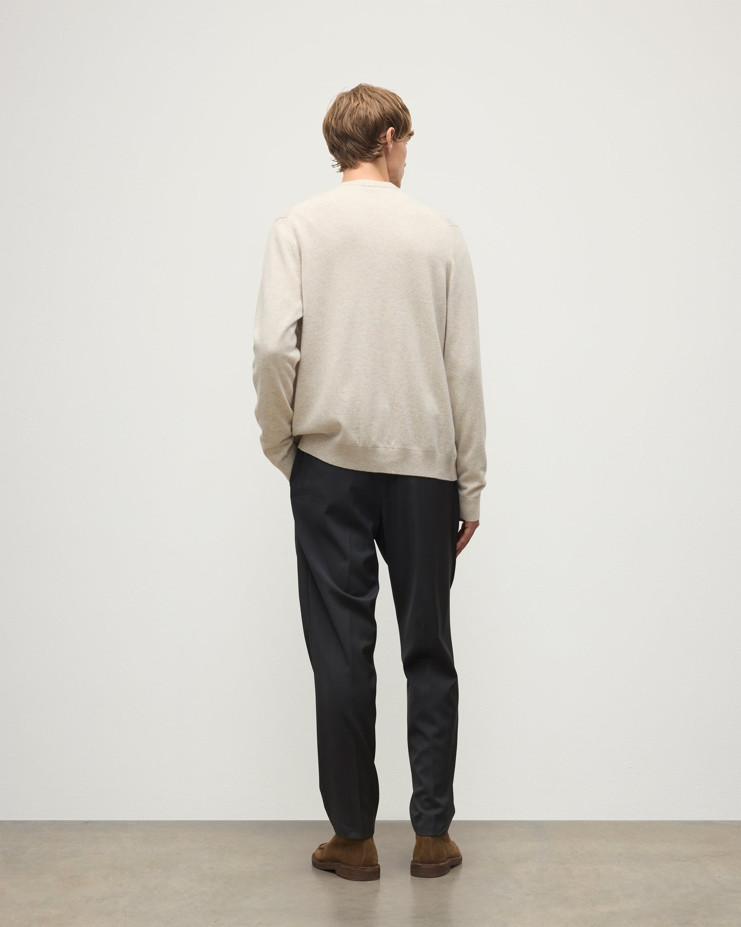 MODEL WEARS JOHNSTONS OF ELGIN MENS RORY VEE NECK CLASSIC CARDIGAN NATURAL 100% CASHMERE OVER A MATCHING V NECK SWEATER WITH GREY TROIUSERS KAP05576HA0402