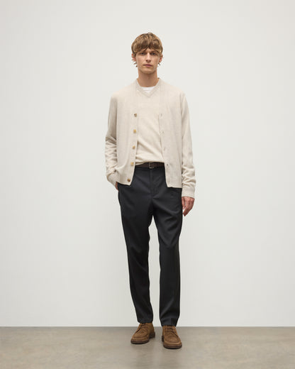 MODEL WEARS JOHNSTONS OF ELGIN MENS RORY VEE NECK CLASSIC CARDIGAN NATURAL 100% CASHMERE OVER A MATCHING V NECK SWEATER WITH GREY TROIUSERS KAP05576HA0402