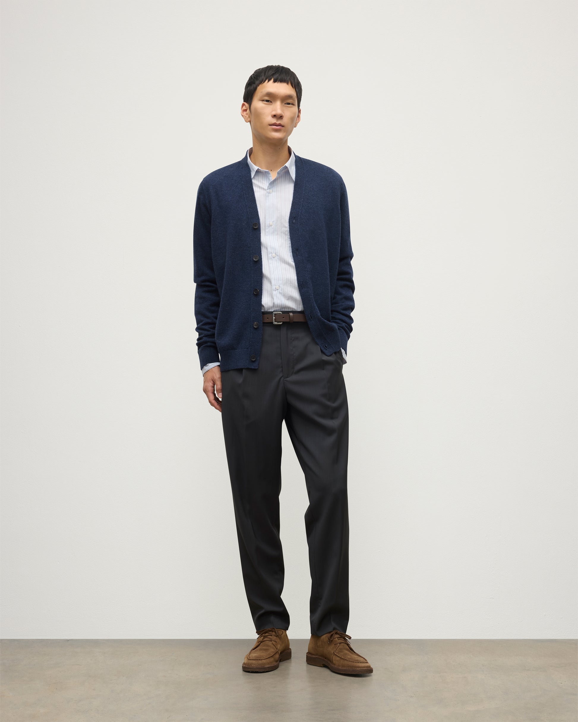 MODEL WEARS JOHNSTONS OF ELGIN MENS RORY VEE NECK CLASSIC CARDIGAN NAVY 100% CASHMERE OVER A LIGHT BLUE SHIRT WITH NAVY TROUSERS KAP05576HD7350