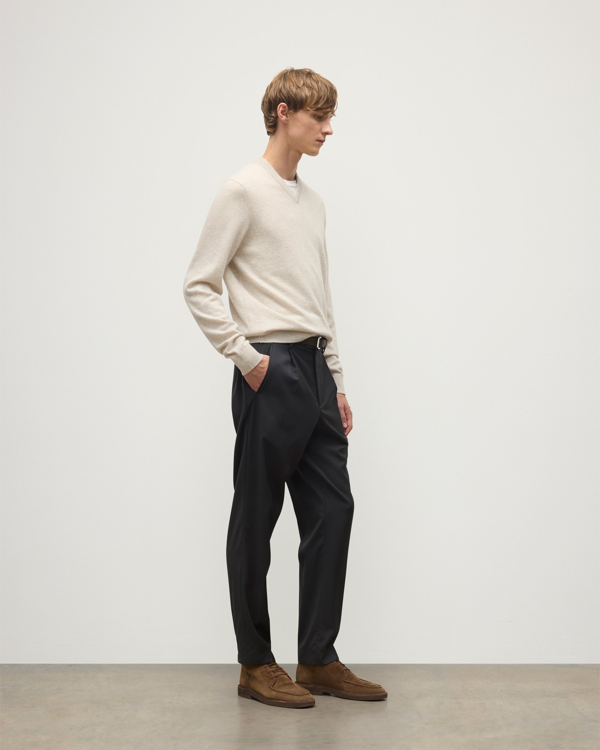 MODEL WEARS JOHNSTONS OF ELGIN MENS RORY VEE NECK CLASSIC JUMPER NATURAL 100% CASHMERE, OVER A WHITE T-SHIRT WITH NAVY TROUSERS  KAP05594HA0402