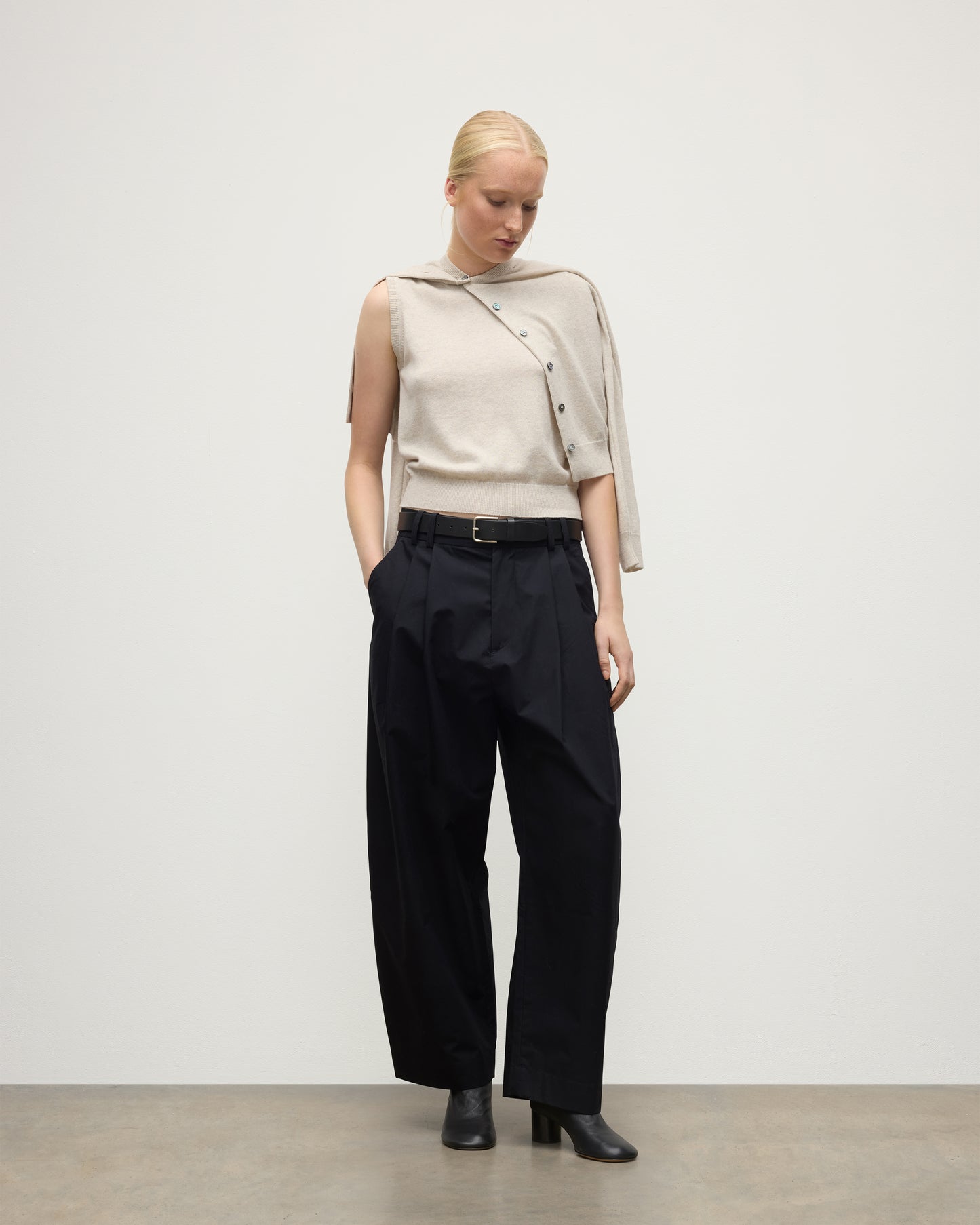 MODEL WEARING JOHNSTONS OF ELGIN WOMENS IRIS CLASSIC CREW CARDIGAN NATURAL 100% CASHMERE OVER MATCHING SLEEVELESS TOP WITH NAVY TROUSERS AND BLACK BOOTS KAP05704HA0402