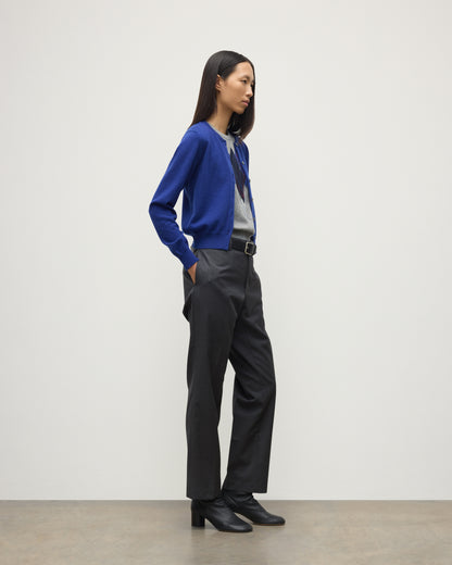 MODEL WEARING JOHNSTONS OF ELGIN WOMENS IRIS CLASSIC CREW CARDIGAN BLUE 100% CASHMERE OVER LE JABOT CASHMERE TANK WITH GREY TROUSERS AND BLACK BOOTS KAP05704SD5326