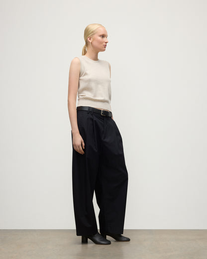 MODEL WEARS JOHNSTONS OF ELGIN WOMENS IRIS CLASSIC SLEEVELESS CREW NATURAL 100% CASHMERE WITH NAVY TROUSERS AND BLACK BOOTS  KAP05705HA0402