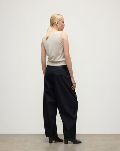 MODEL WEARS JOHNSTONS OF ELGIN WOMENS IRIS CLASSIC SLEEVELESS CREW NATURAL 100% CASHMERE WITH NAVY TROUSERS AND BLACK BOOTS  KAP05705HA0402