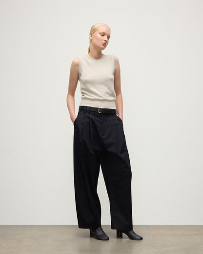 MODEL WEARS JOHNSTONS OF ELGIN WOMENS IRIS CLASSIC SLEEVELESS CREW NATURAL 100% CASHMERE WITH NAVY TROUSERS AND BLACK BOOTS  KAP05705HA0402