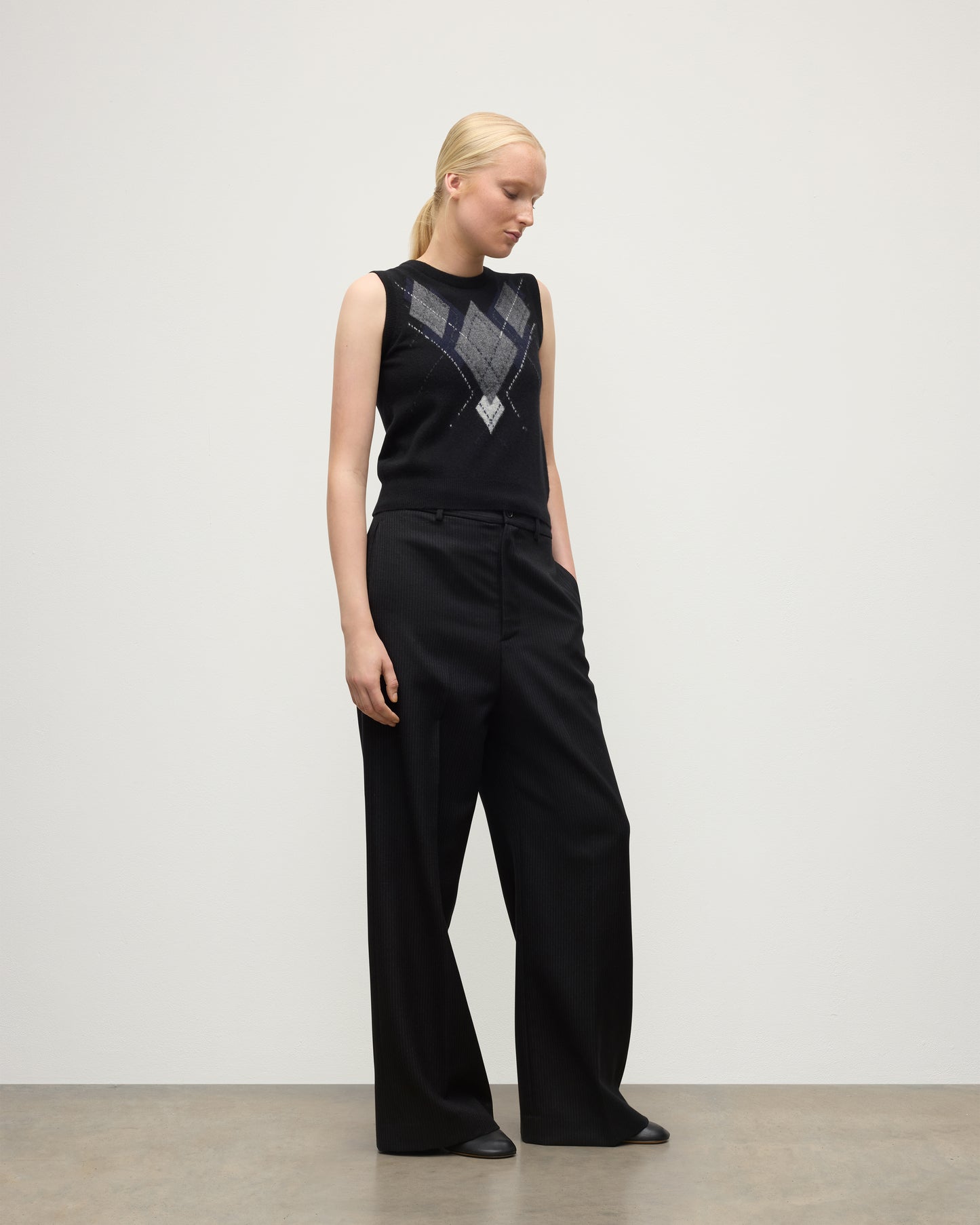 MODEL WEARING JOHNSTONS OF ELGIN WOMENS ARGYLL LE JABOTS SLEEVELESS CREW BLACK 100% CASHMERE WITH BLACK TROUSERS KAP05766JU1609