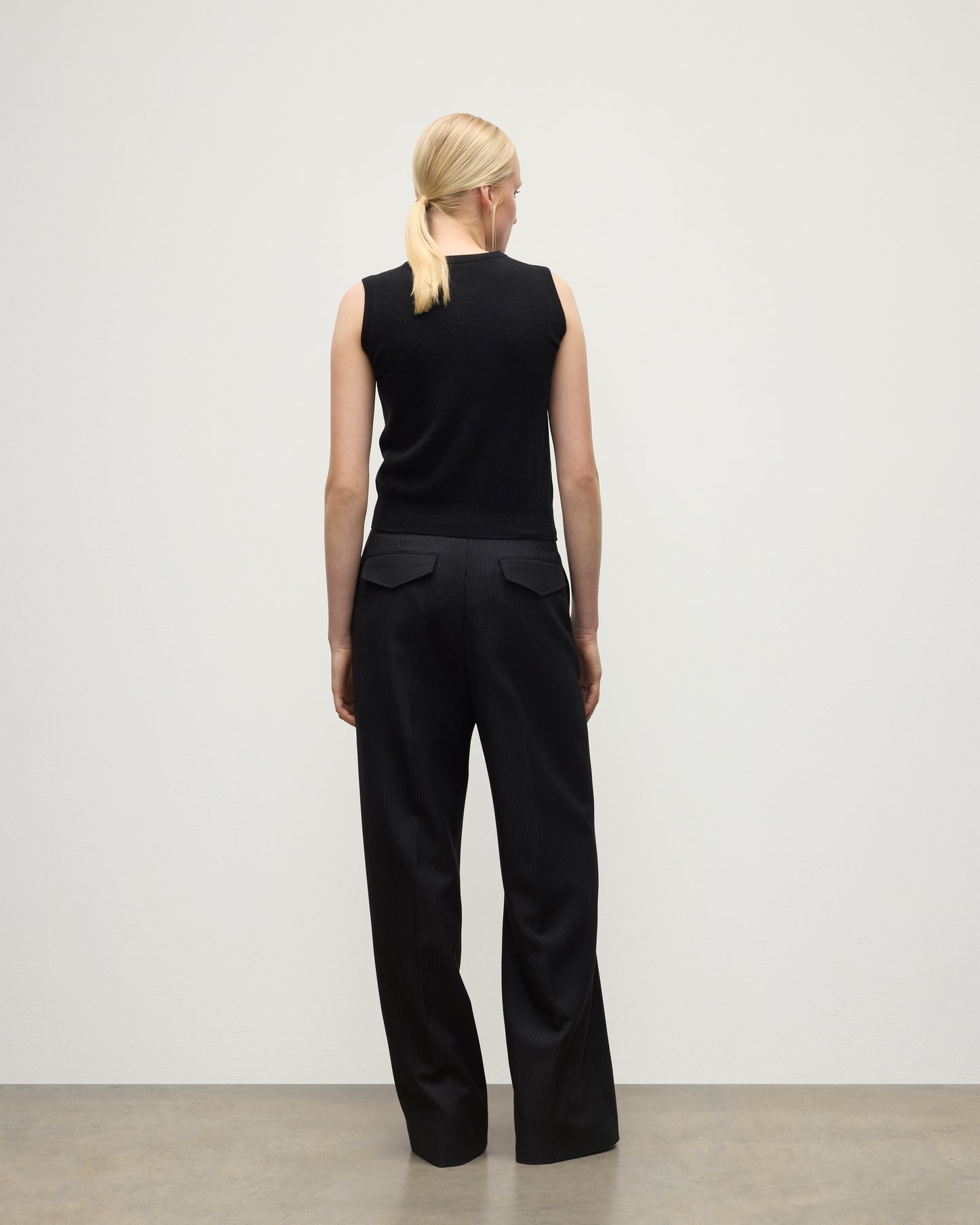 MODEL WEARING JOHNSTONS OF ELGIN WOMENS ARGYLL LE JABOTS SLEEVELESS CREW BLACK 100% CASHMERE WITH BLACK TROUSERS KAP05766JU1609