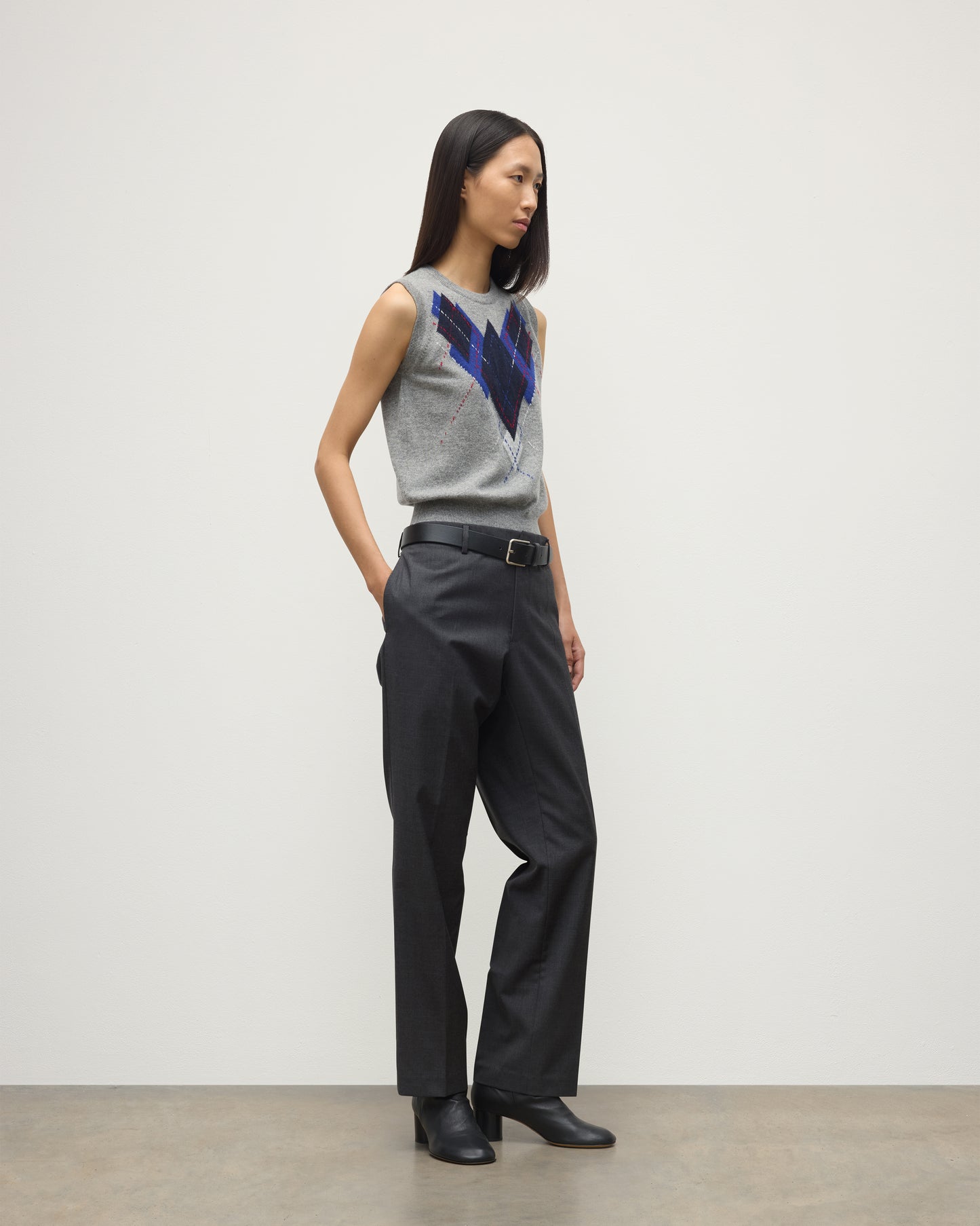 MODEL WEARS JOHNSTONS OF ELGIN WOMENS ARGYLL LE JABOTS SLEEVELESS CREW GREY 100% CASHMERE WITH BELTED GREY TROUSERS AND BLACK BOOTS KAP05766JU1611