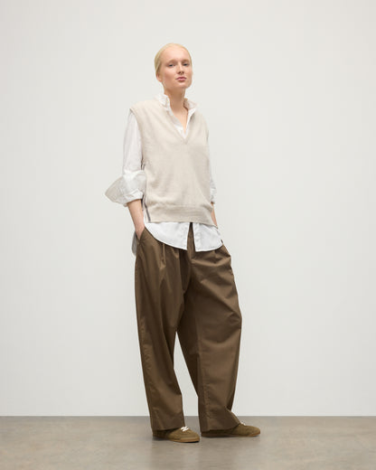 MODEL WEARS JOHNSTONS OF ELGIN WOMENS TILDA SLEEVELESS VEE NATURAL 100% CASHMERE OVER A WHITE SHIRT, WITH BROWN TROUSERS KAP05767Q25969