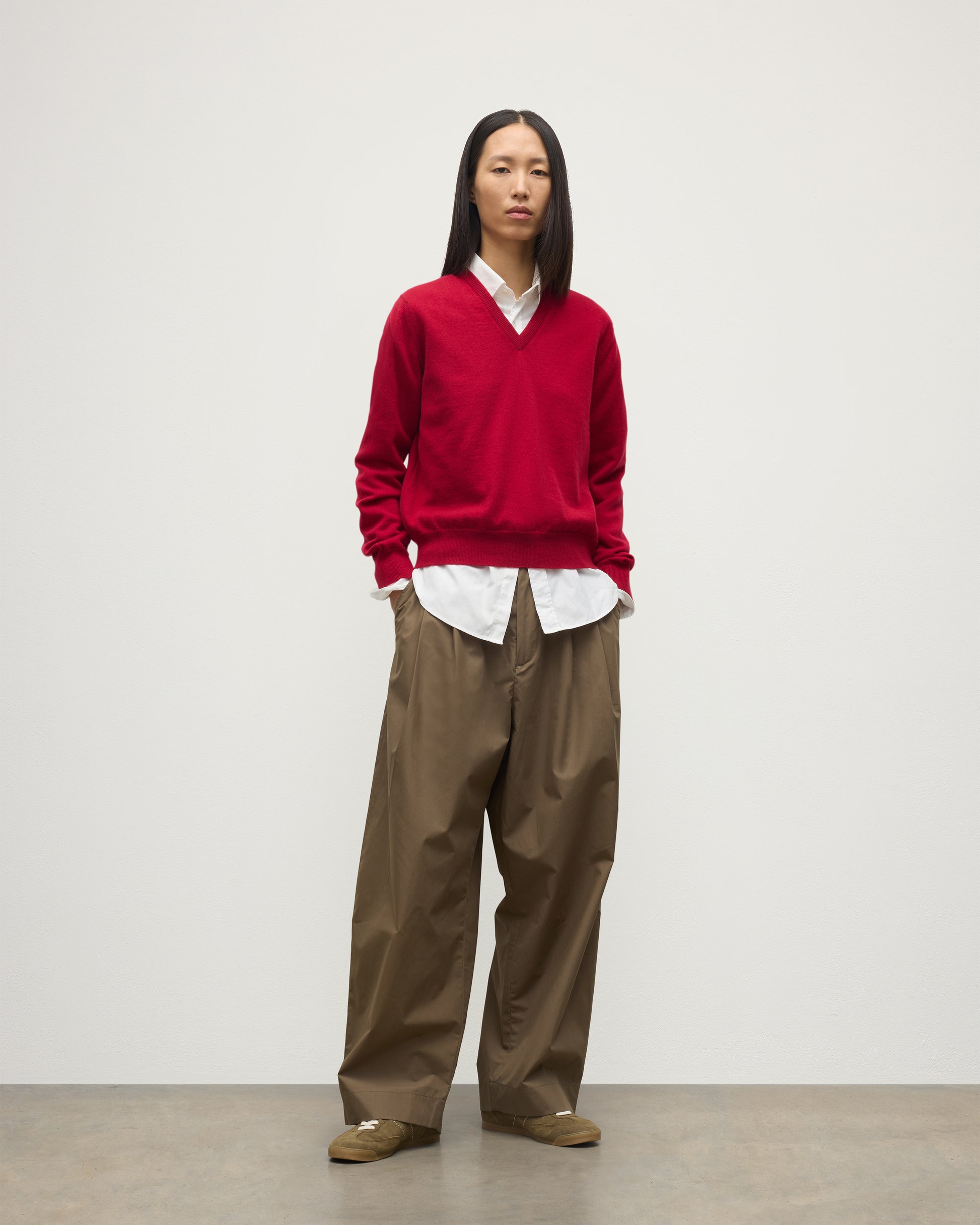 MODEL WEARING JOHNSTONS OF ELGIN WOMENS LUNAN CLASSIC VEE SWEATER RED 100% CASHMERE OVER WHITE SHIRT WITH BROWN TROUSERS KAP05807SE5325