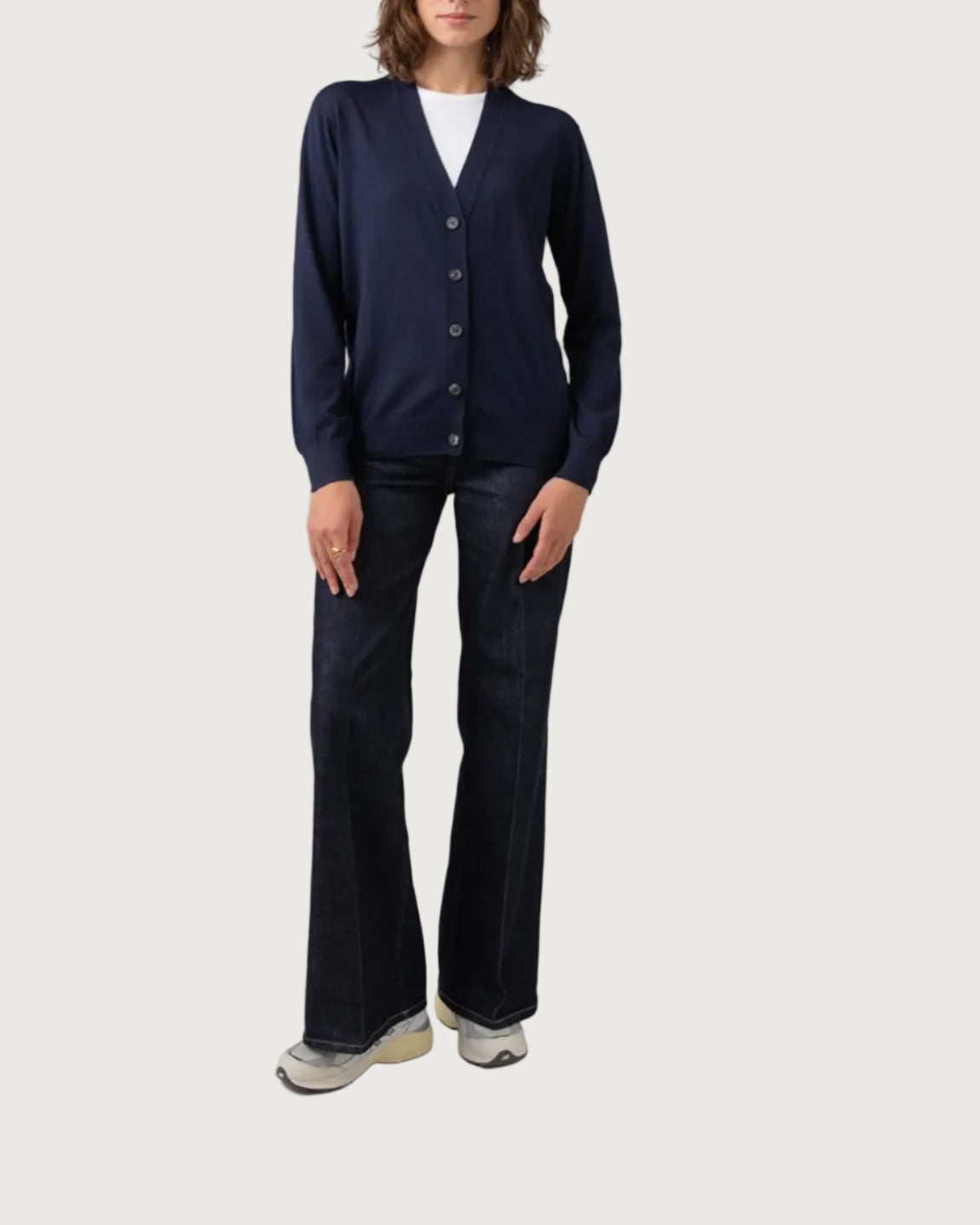 Person wearing a navy cardigan and dark pants on a plain background KDI00684SD7563