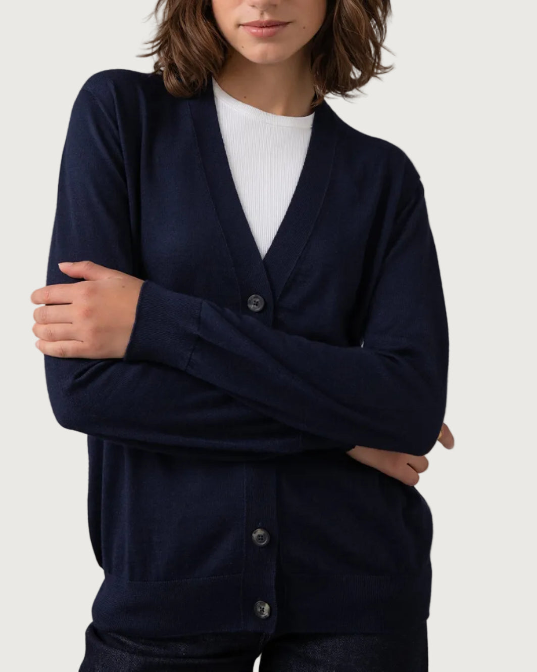 Woman wearing a navy cardigan over a white shirt against a plain background KDI00684SD7563