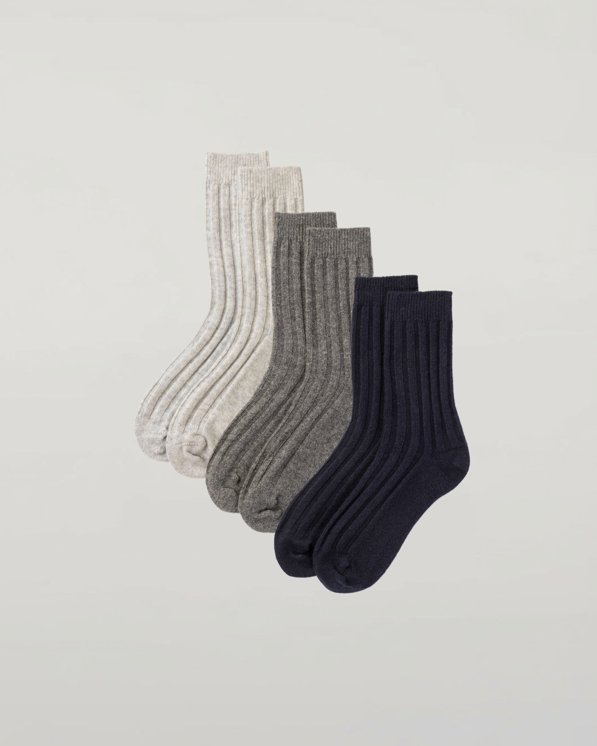 Johnstons of Elgin set of three pairs of cashmere socks in navy, light grey, and mid grey on a light grey background 2025GIFTSET4A