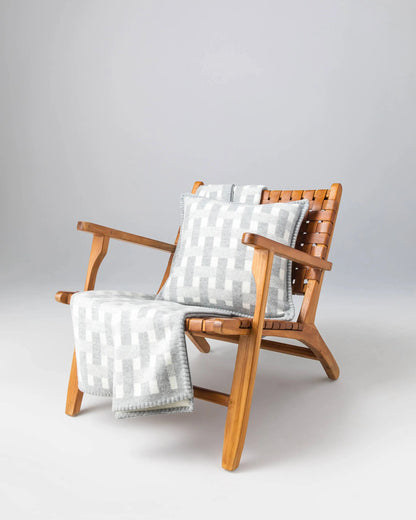 2025 Johnstons of Elgin Interiors Collection Light Grey & White Blanket Stitched Basketweave Throw on a wooden chair  TB000500RU7442ONE