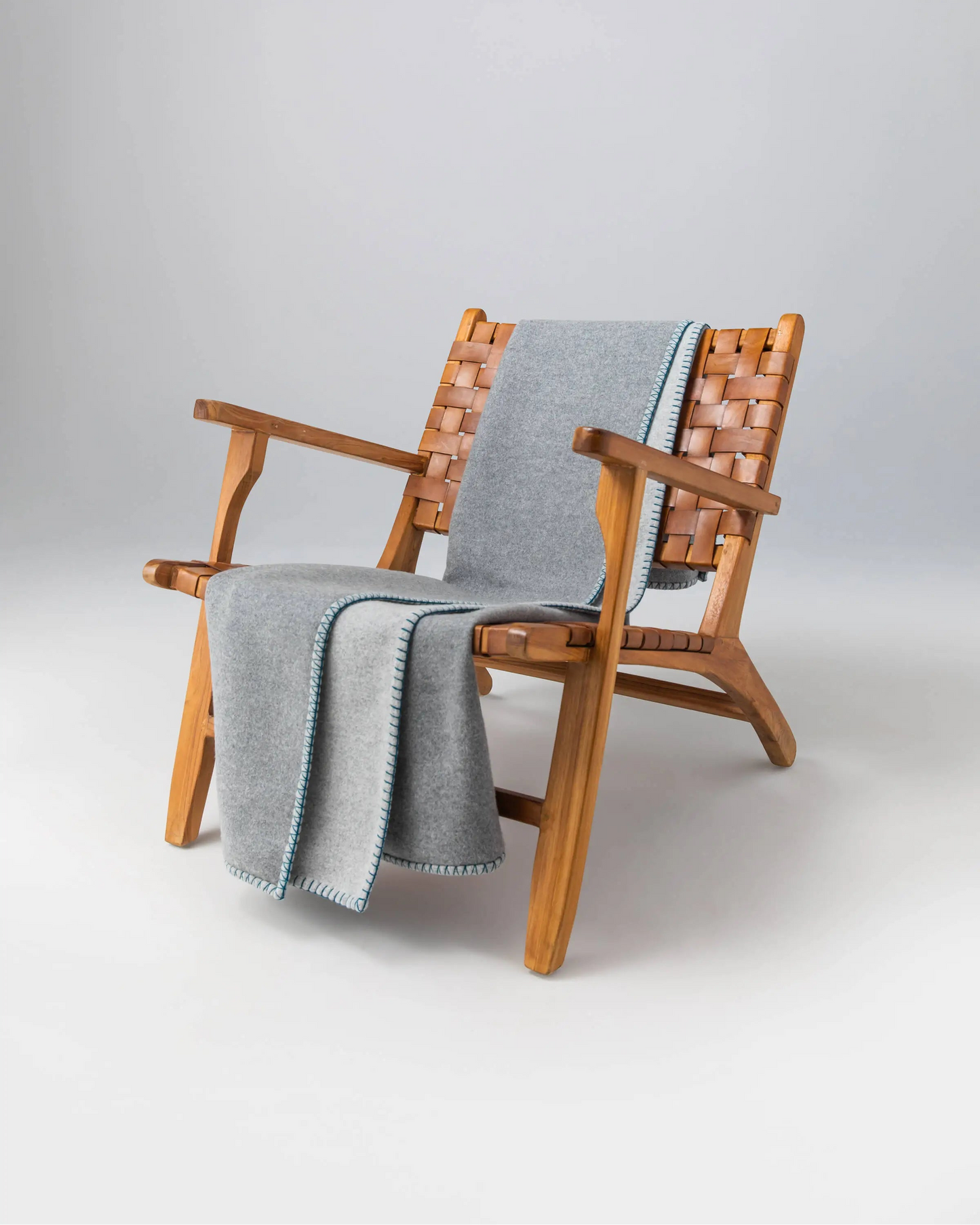 2025 Johnstons of Elgin Interiors Collection Silver & Grey Reversible Blanket Stitched Throw on a wooden chair  TB000500RU7560ONE