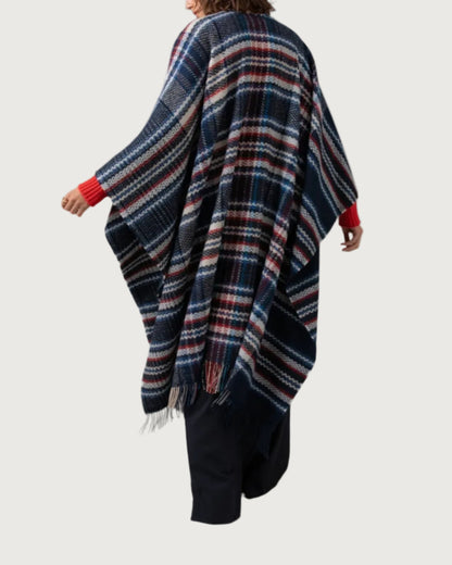 Back of Johnstons of Elgin Cashmere Wool Blend Textured Donegal Cape Navy Multi worn over an Orkney Red Cable Sweater and Navy Trousers on a grey background TB000632RU7354ONE