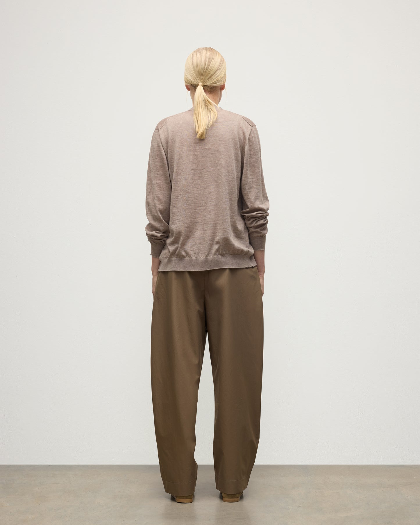 FEMALE MODEL WEARING JOHNSTONS OF ELGIN FORSYTH SUPERFINE VEE NECK CARDIGAN LIGHT BROWN WITH BROWN WIDE LEG TROUSERS UAI05740HB0273