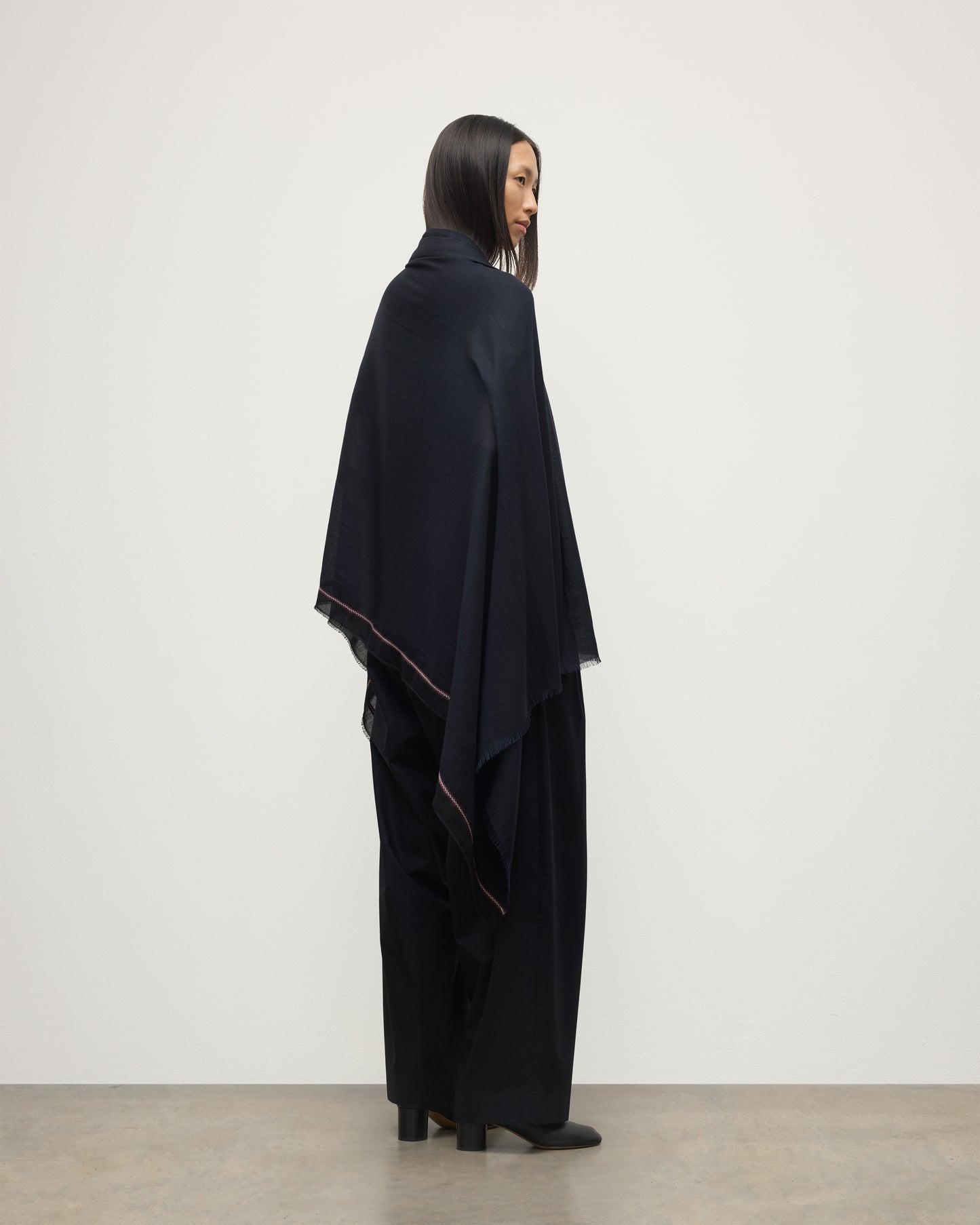 FEMALE MODEL WEARS JOHNSTONS OF ELGIN IVES CHEVRON BORDER SCARF NAVY 100% CASHMERE DRAPED OVER HER SHOULDERS OVER A NAVY CASHMERE SWEATER   WA002446RU7699ONE