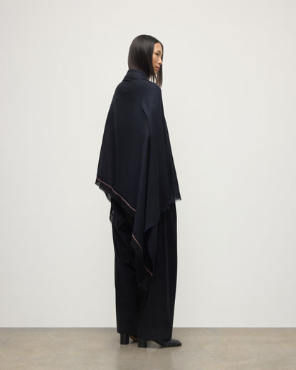 FEMALE MODEL WEARS JOHNSTONS OF ELGIN IVES CHEVRON BORDER SCARF NAVY 100% CASHMERE DRAPED OVER HER SHOULDERS OVER A NAVY CASHMERE SWEATER   WA002446RU7699ONE