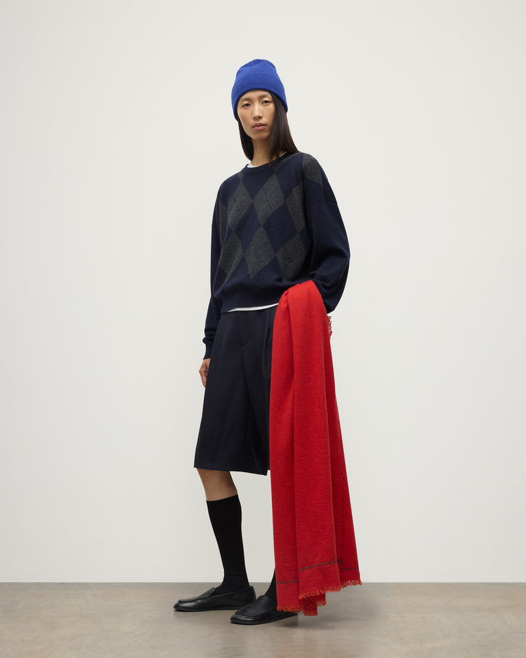 MODEL WEARING JOHNSTONS OF ELGIN USAN SEMI PLAIN SCARF RED 100% CASHMERE WITH CLAN ARGYLL CASHMERE SWEATER, KILT AND BRAEMAR BLUE BEANIE HAE02655SD5326ONE
