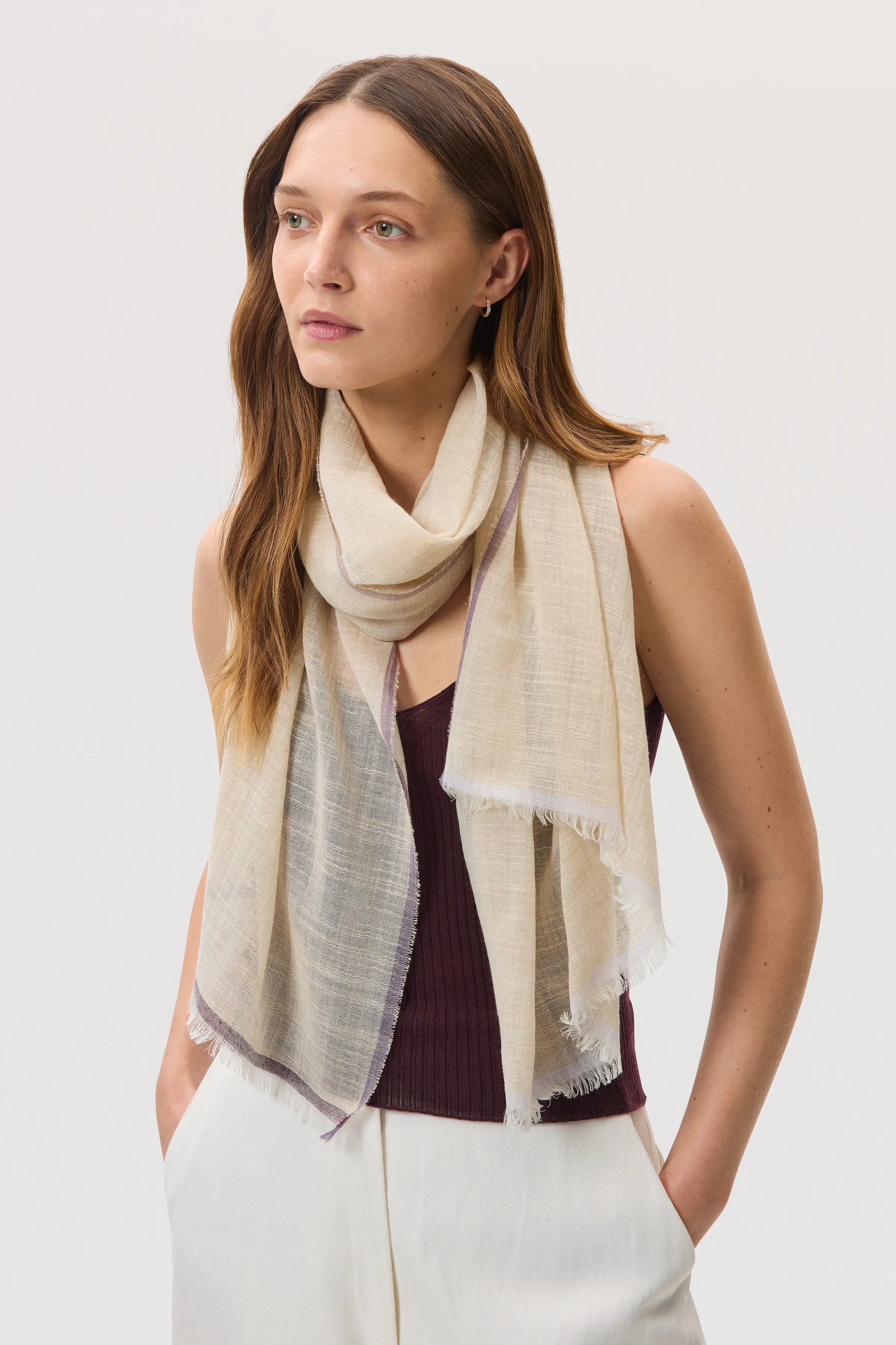 Female model wearing Johnstons of Elgin SS25 Accessories Natural Colour Border Lightweight Scarf over our rosewood superfine cashmere vest top, on a white background WB002693RU7595ONE