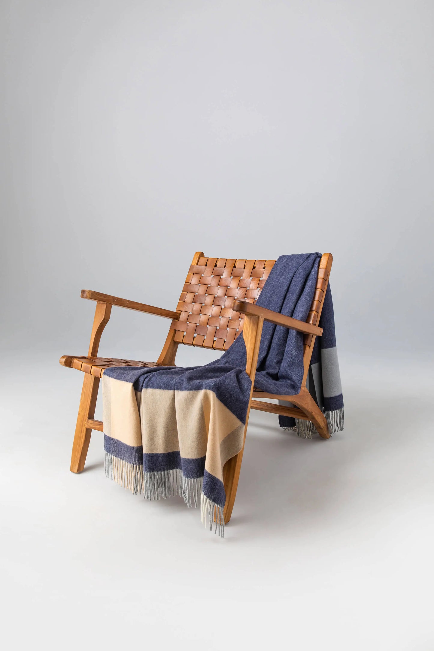 2025 Johnstons of Elgin Interiors Collection Dark Block Border Wool Throw on a wooden chair WDC01871RU7454ONE